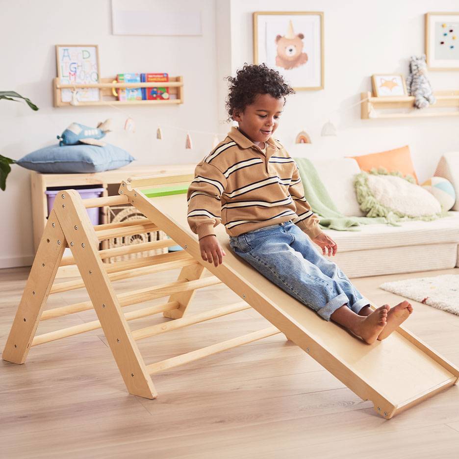 Un enfant joue sur un toboggan et une échelle en bois dans une chambre d'enfant.