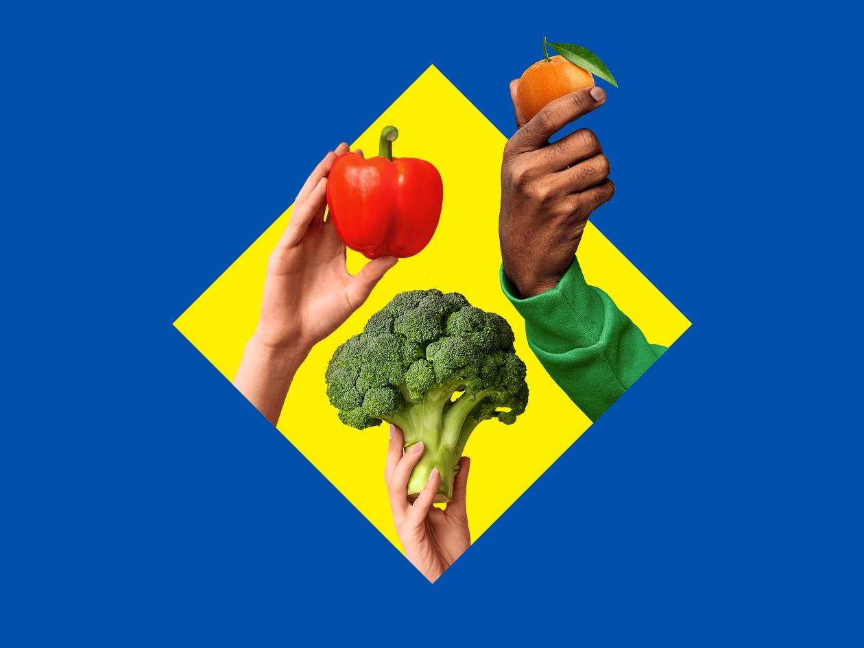 Mains tenant un poivron rouge, un brocoli et une mandarine sur fond bleu et jaune.