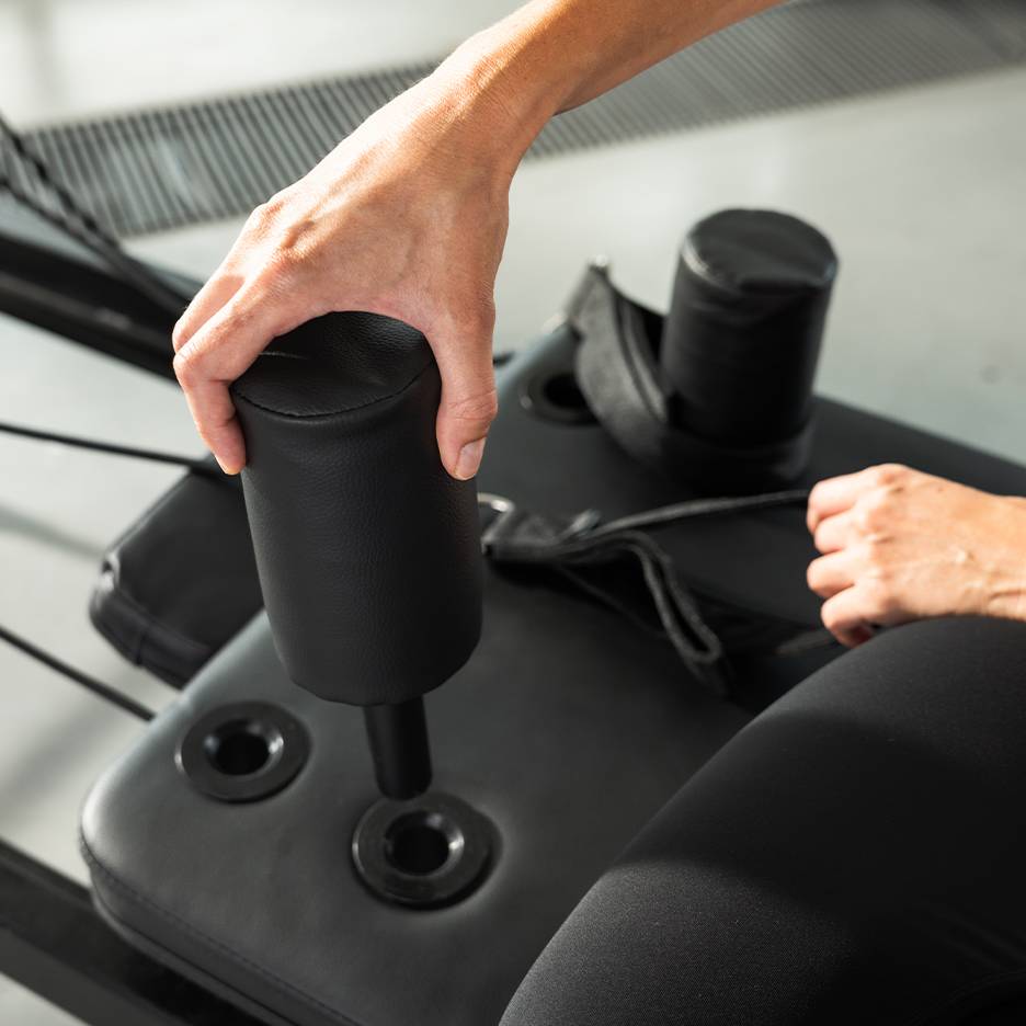 Personne ajustant un appareil d'exercice rembourré noir.