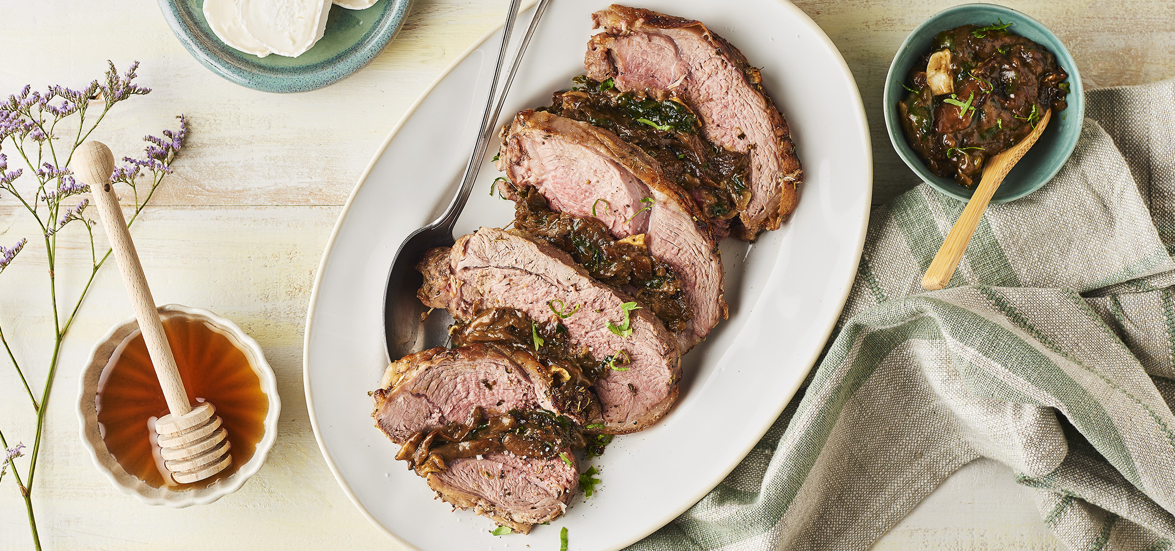 Rôti de bœuf tranché avec sauce aux herbes, miel et fleurs de statice.