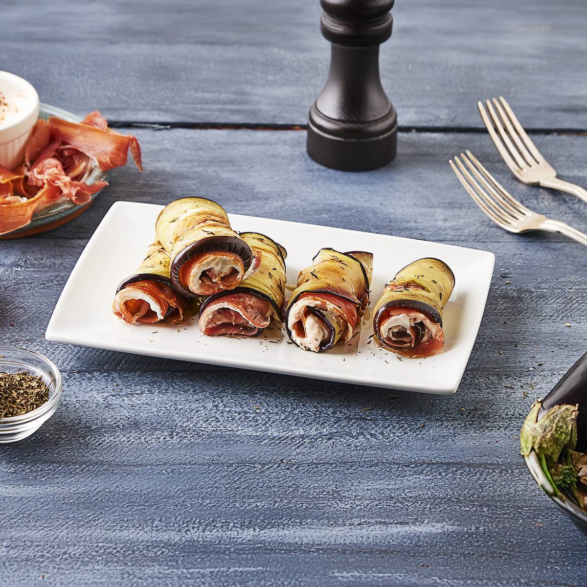 Rouleaux d'aubergines farcis au jambon et au fromage sur une assiette blanche.