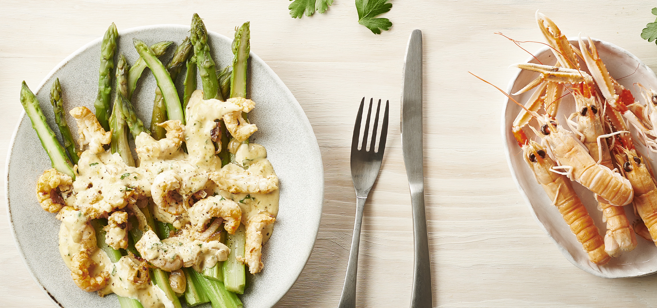 Plat d'asperges vertes avec sauce crémeuse et crevettes, accompagné de langoustines.
