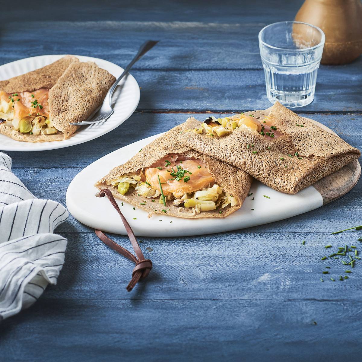 Crêpes au saumon et aux poireaux, servies sur une table en bois.