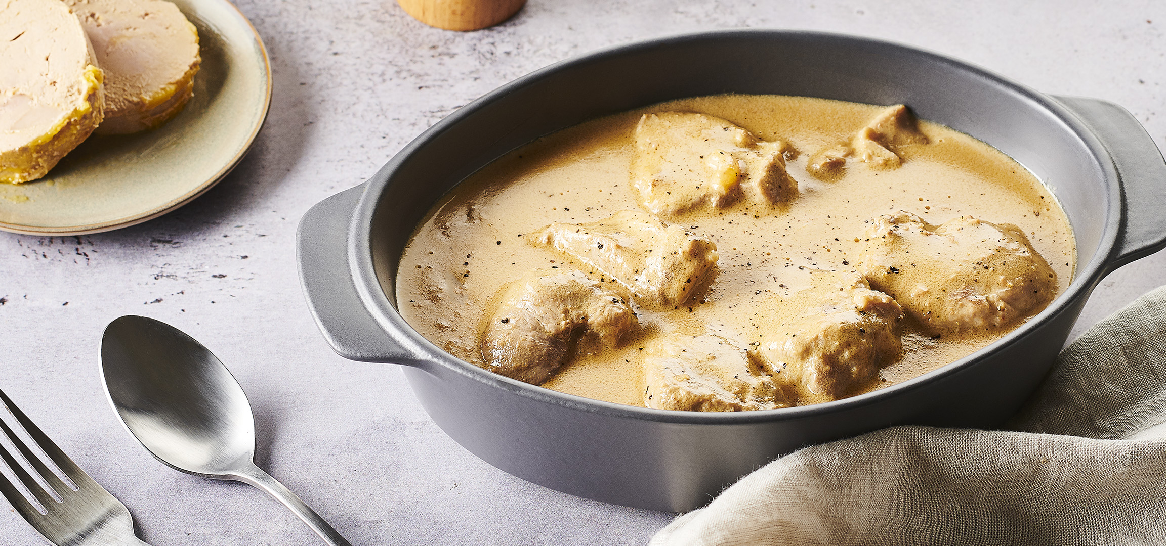 Plat de poulet en sauce crémeuse avec du riz, du foie gras et une carafe de lait.