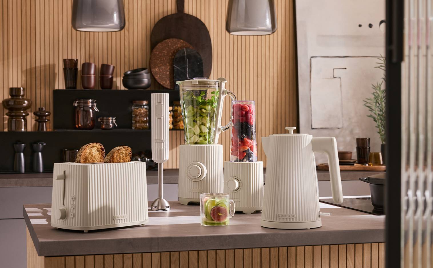 Une cuisine moderne avec un grille-pain, un mixeur plongeant, un blender et une bouilloire de couleur crème.