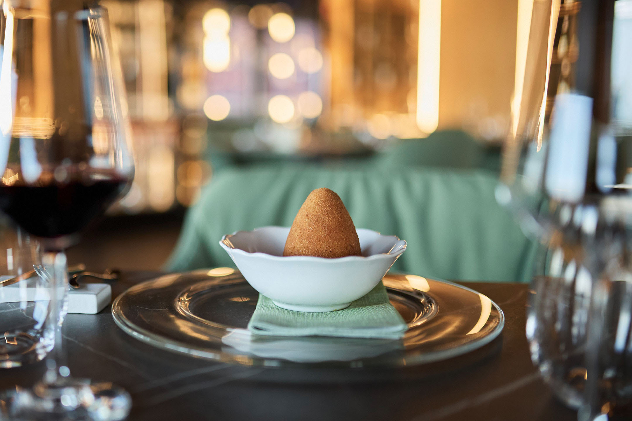 Arancini doré dans un bol blanc sur une table de restaurant élégante.