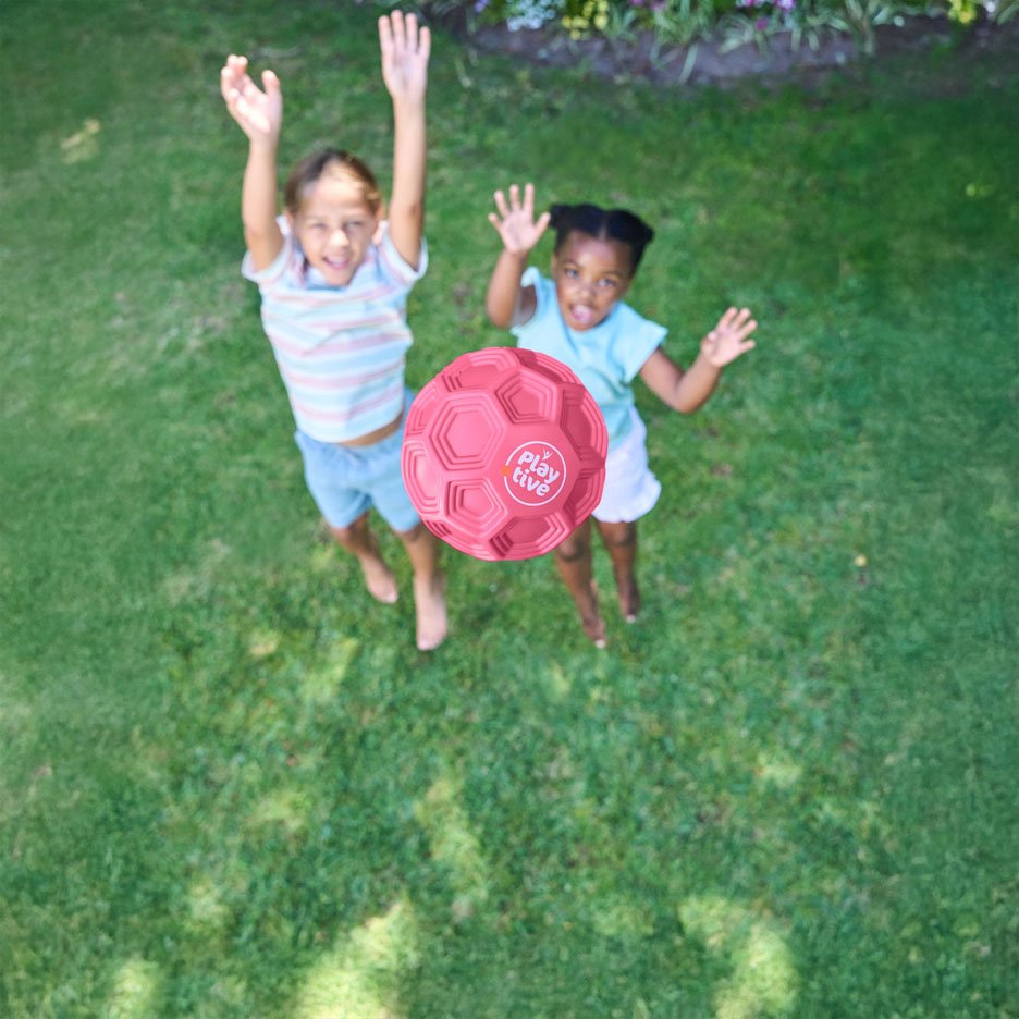 Deux enfants jouent avec un ballon rose en extérieur.