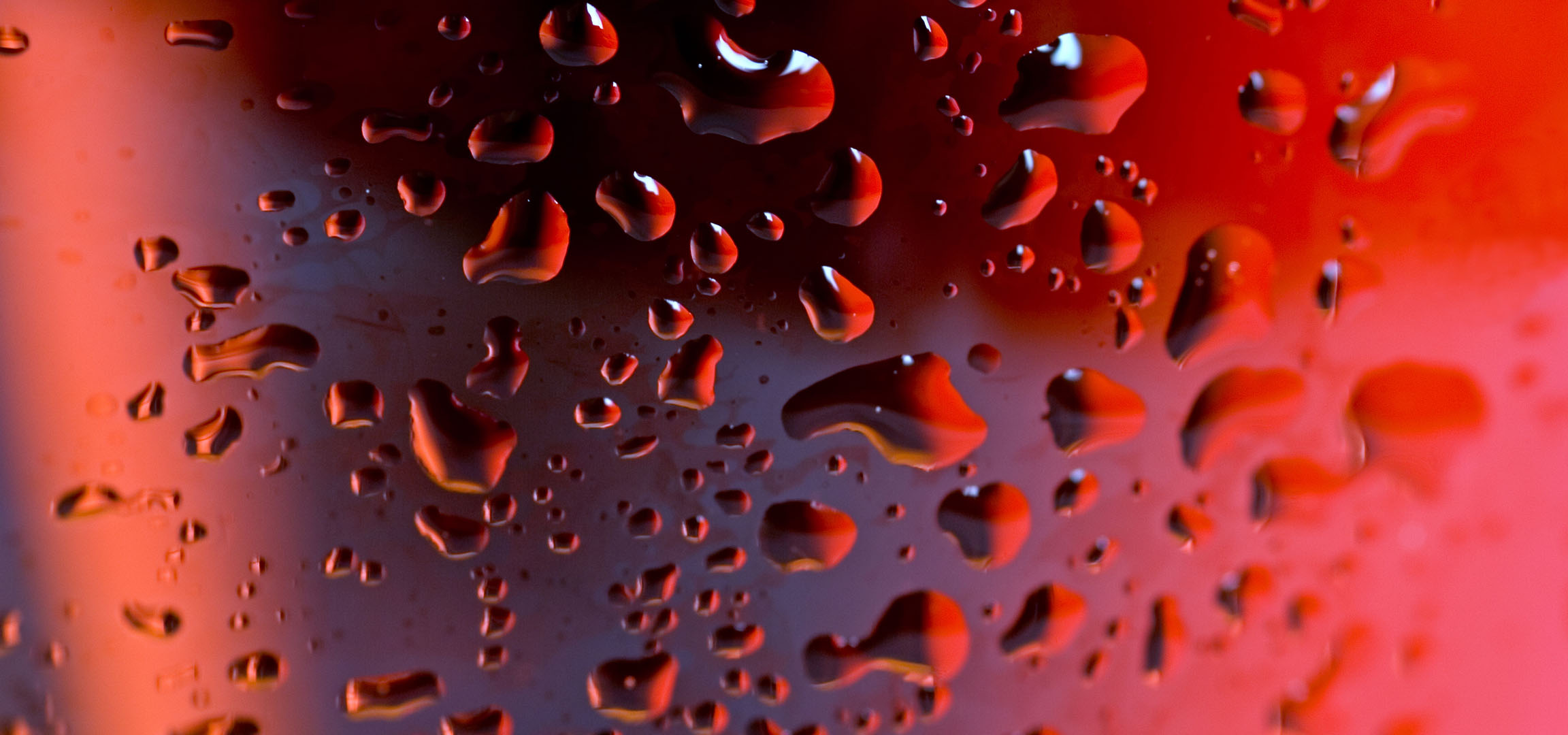 Gouttes d'eau rouges sur une surface avec un arrière-plan flou