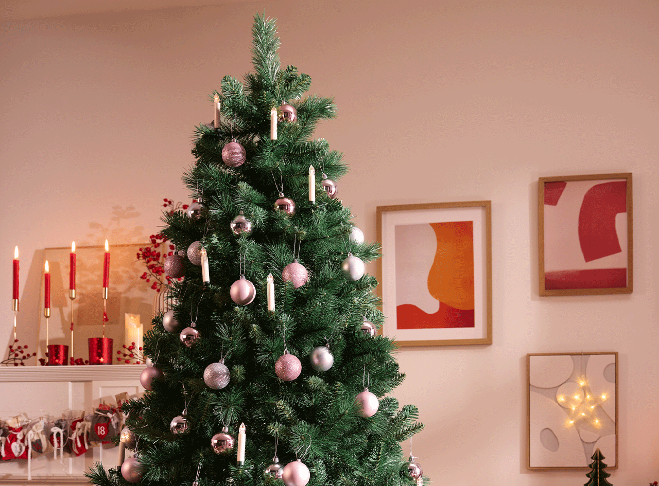Sapin de Noël décoré de boules roses et argentées, avec des bougies et des cadres abstraits.