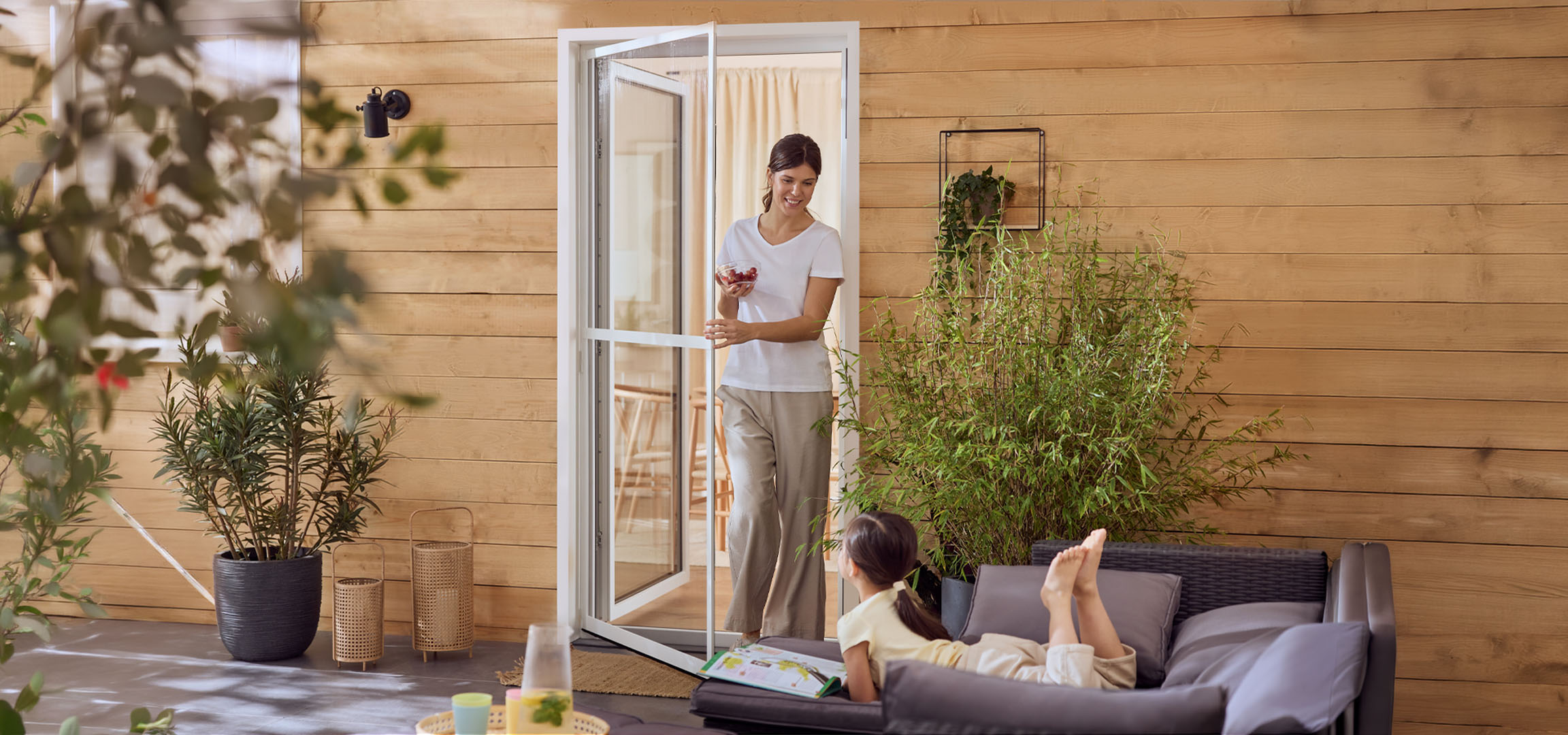 Femme et fille profitant d'un patio avec mobilier d'extérieur et plantes.