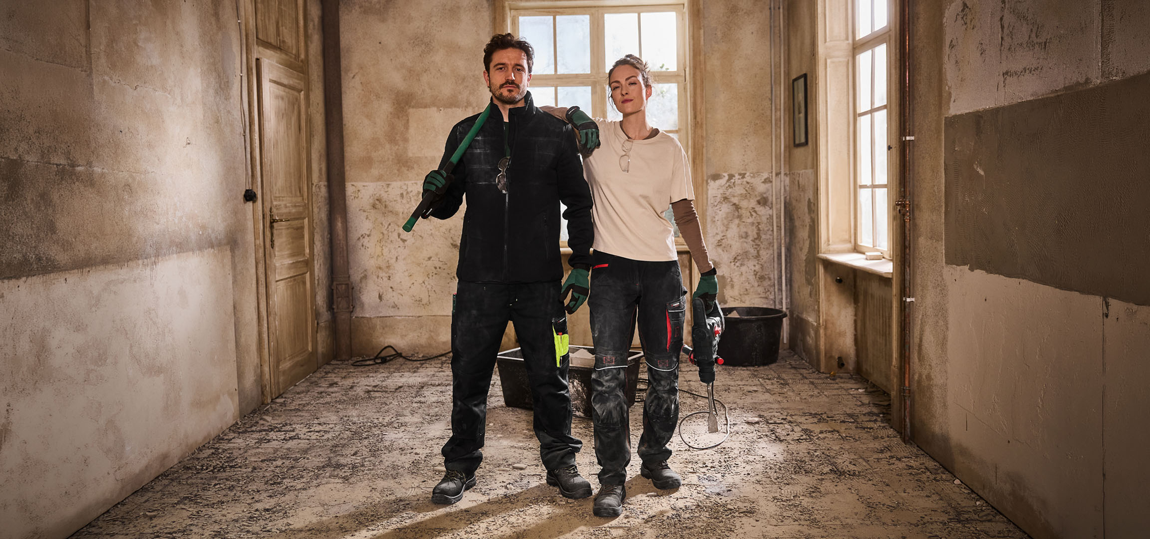 Deux ouvriers du bâtiment en tenue de travail avec des outils sur un chantier.