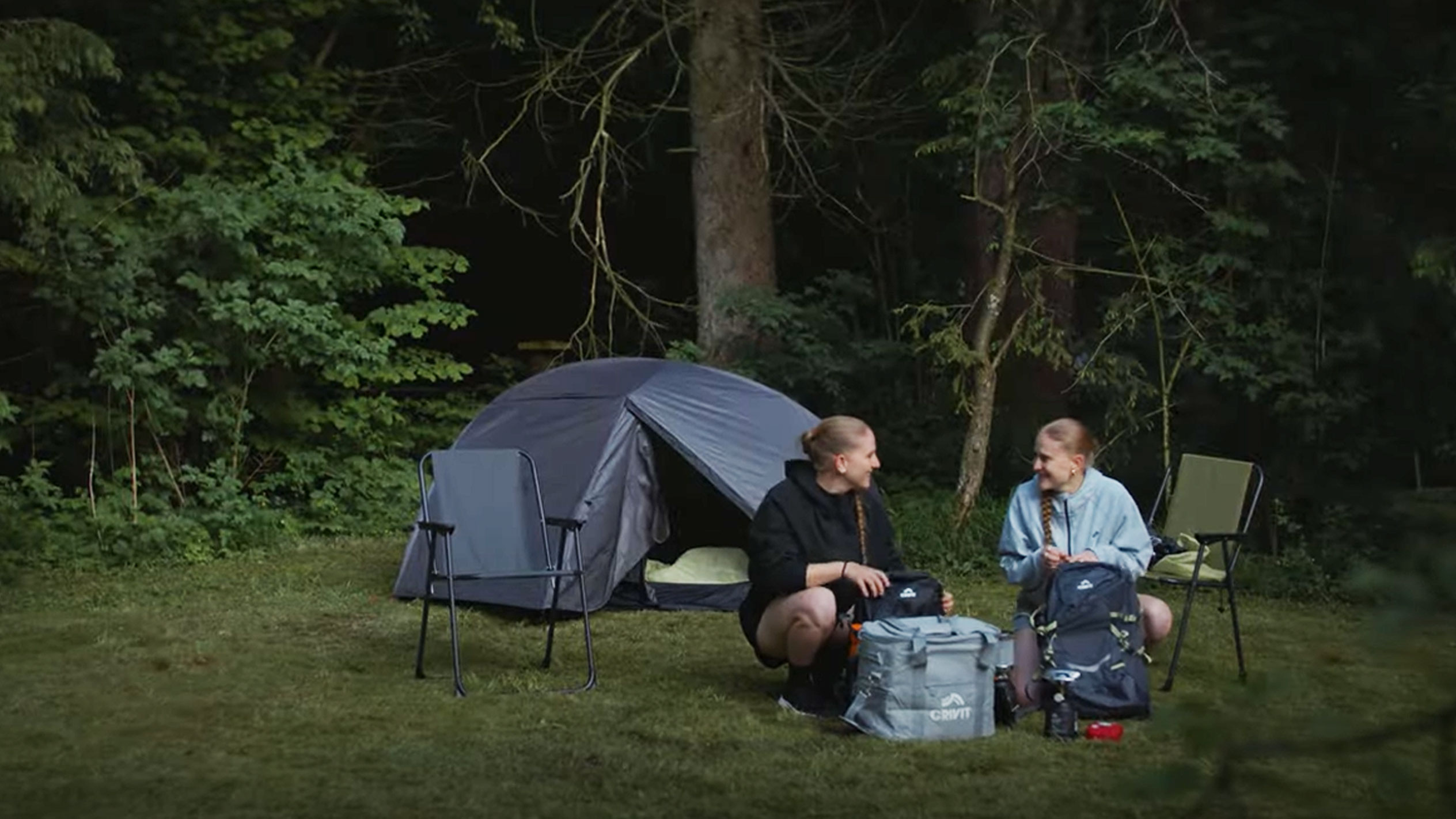 Deux femmes campent avec une tente Crivit et des chaises pliantes.