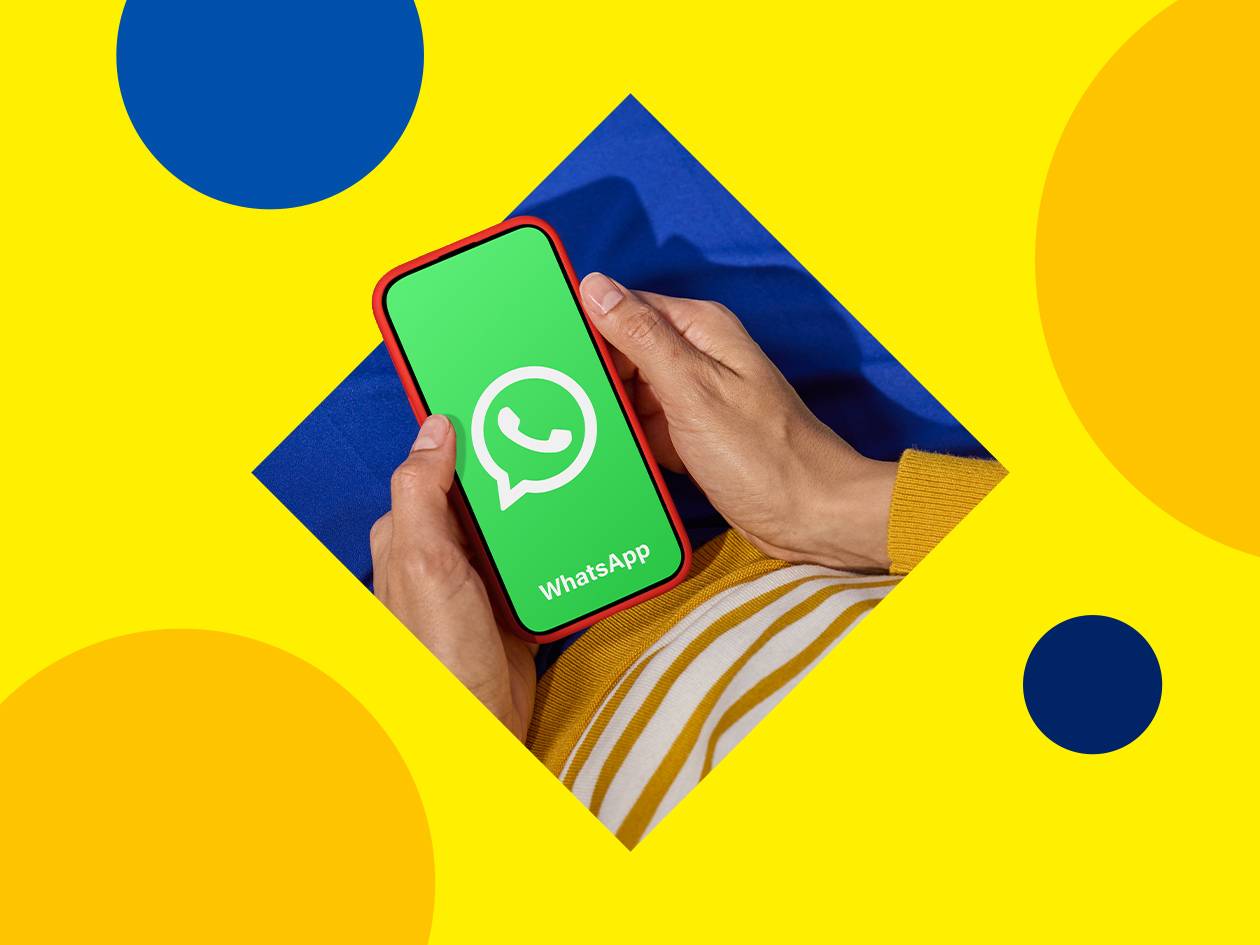 Mains tenant un smartphone affichant une application de messagerie sur fond jaune et bleu.