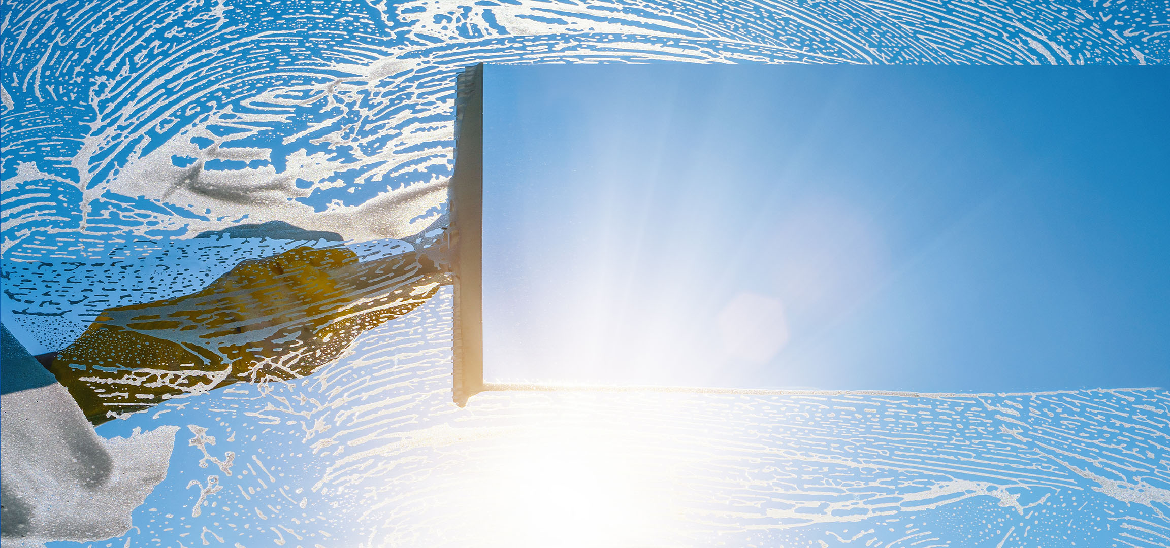 Nettoyage de vitre avec de la mousse de savon sur un ciel bleu.