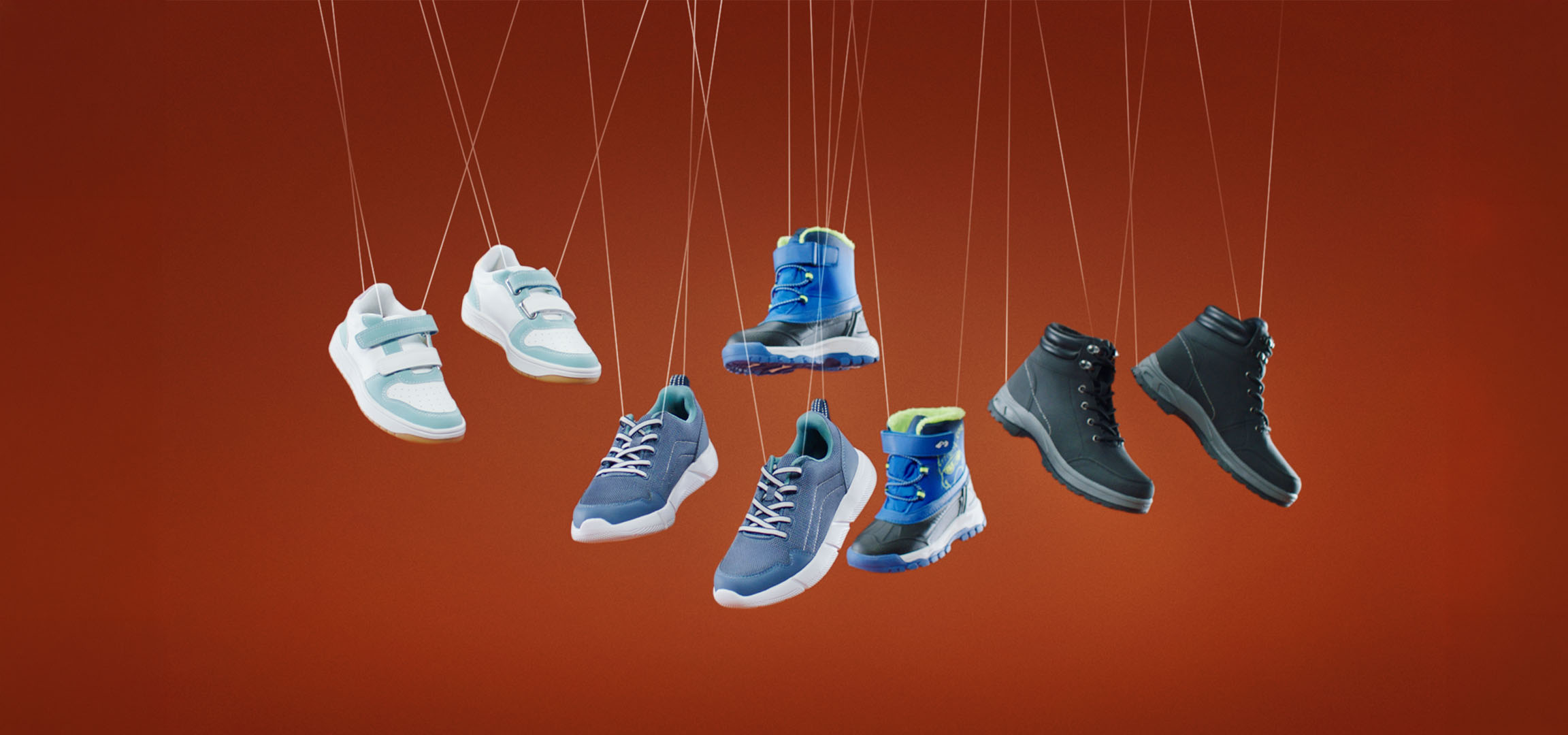 Diverses chaussures pour enfants, y compris des baskets et des bottes, suspendues à des ficelles.