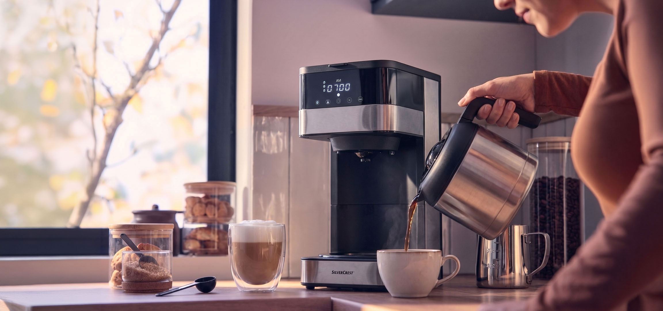 aiLabeling.aiLabelForImageAltText: Machine à café versant du café dans une tasse, avec une fenêtre lumineuse en arrière-plan.