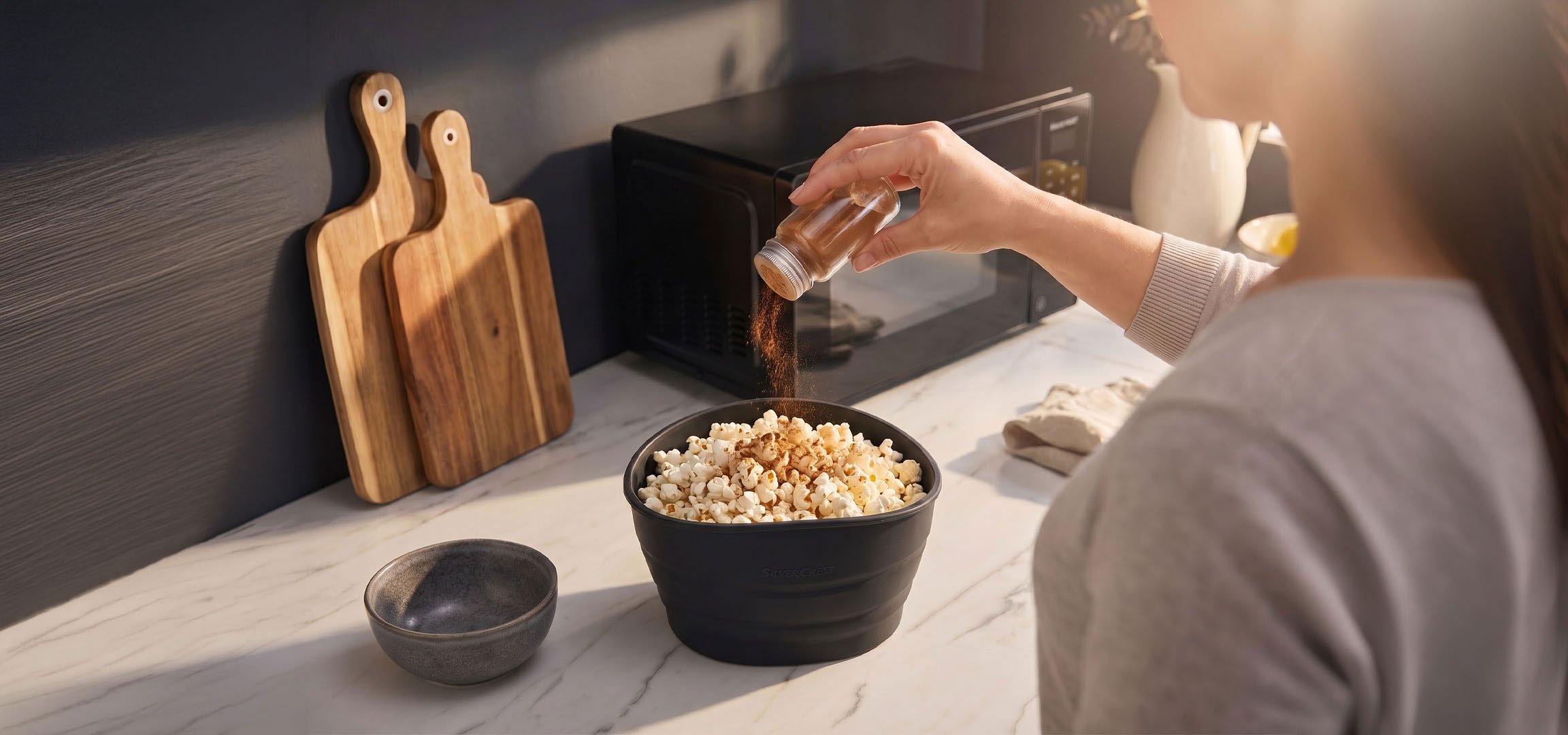 aiLabeling.aiLabelForImageAltText: Popcorn dans un bol noir assaisonné d'épices, à côté de planches à découper en bois.