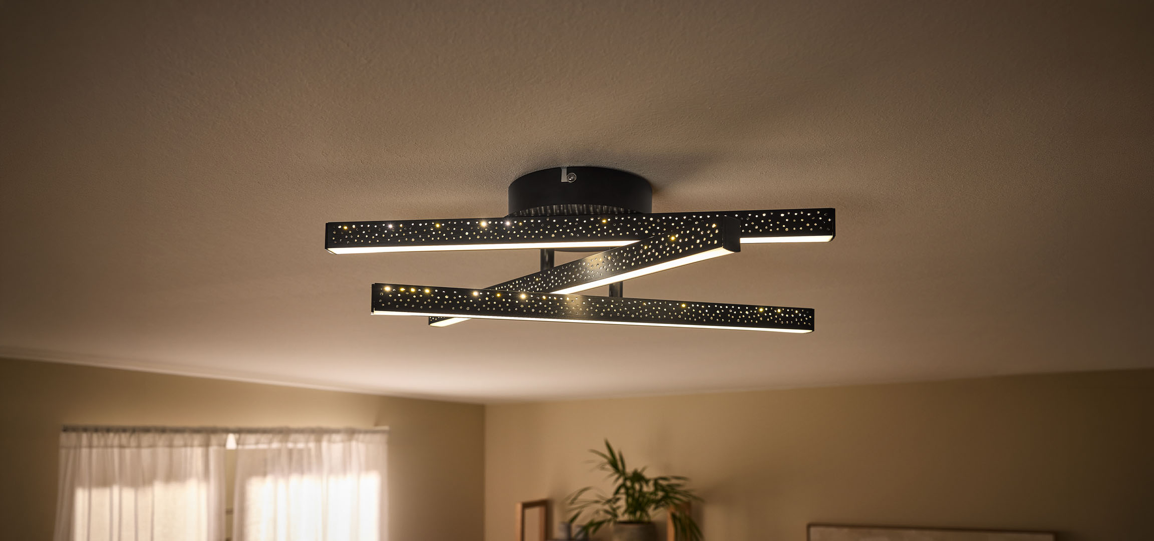 Plafonnier LED moderne avec barres noires perforées et lumière chaude.