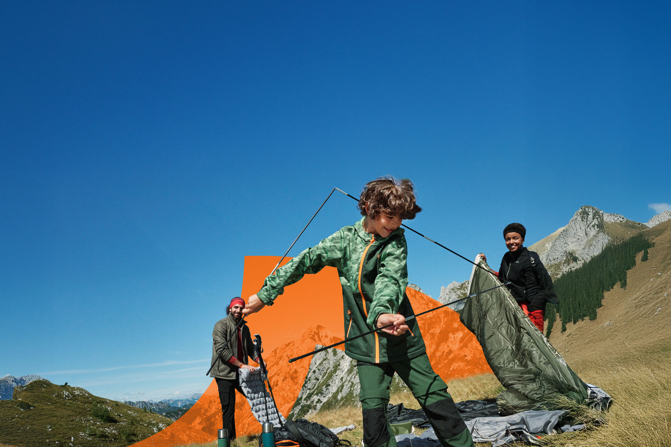 Famille montant une tente en montagne, vêtue de vêtements de randonnée et utilisant du matériel de camping.