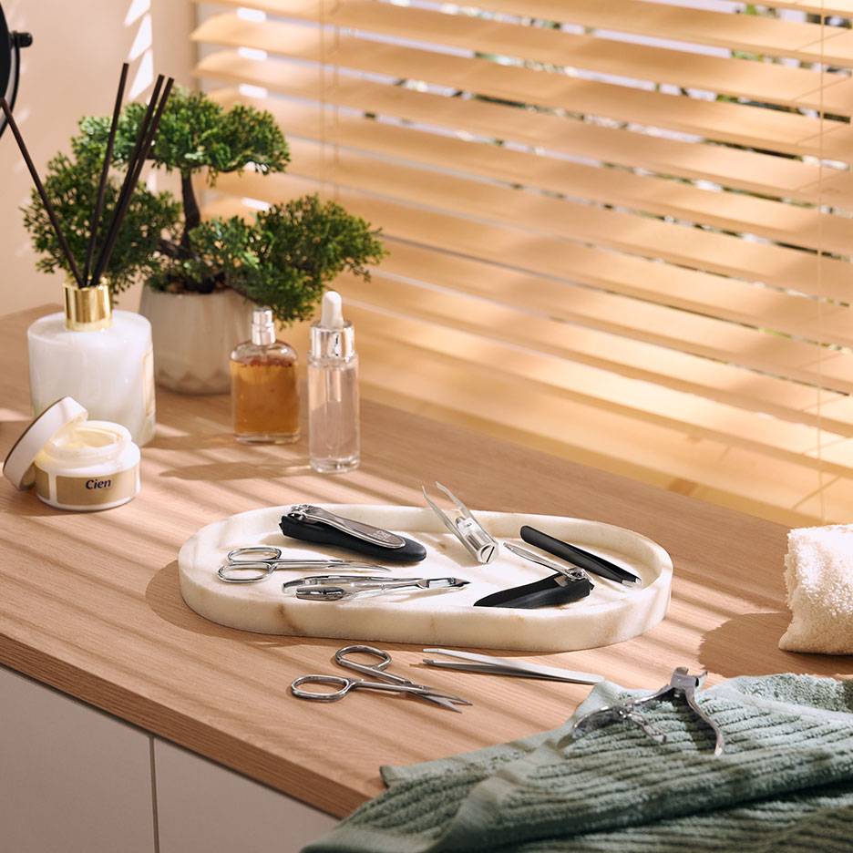 Kit de manucure sur plateau en marbre, avec cosmétiques et plantes sur surface en bois.