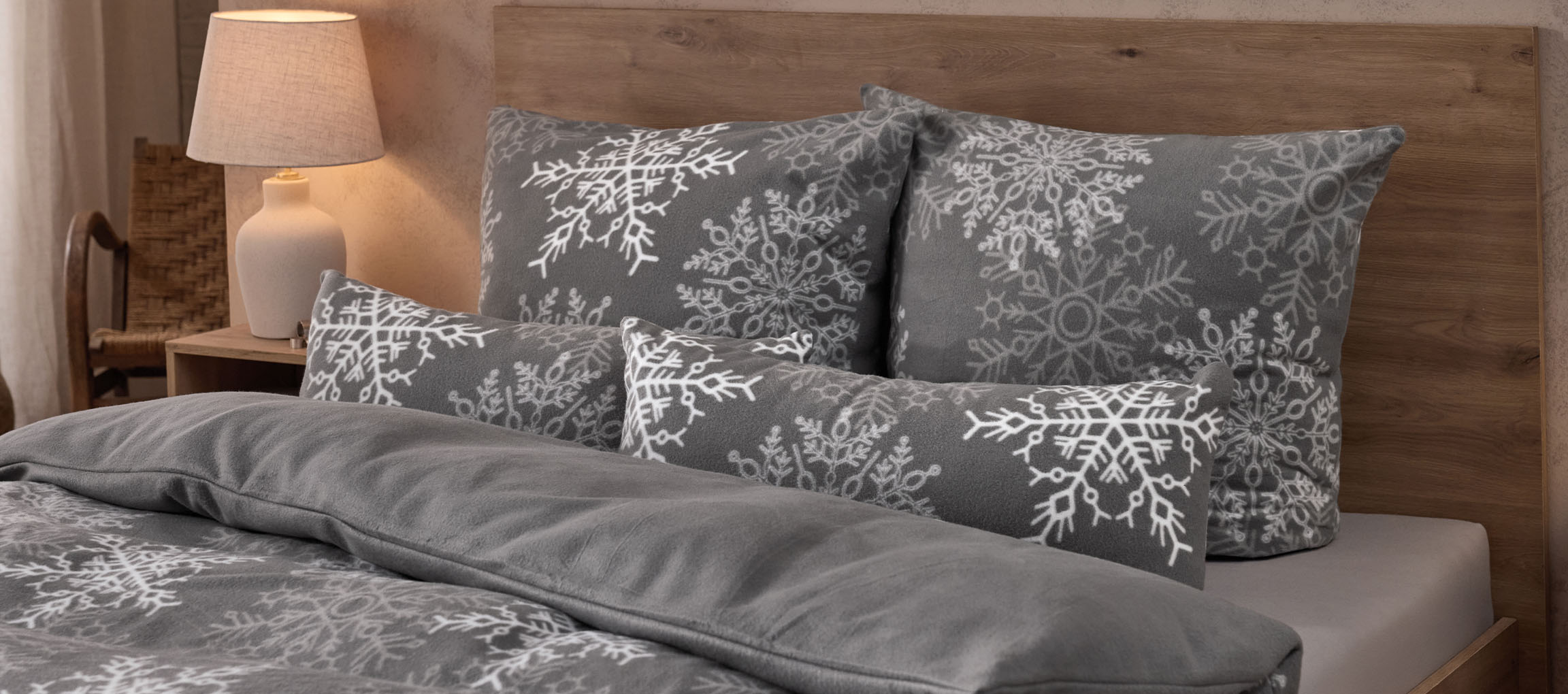 Parure de lit grise à motifs de flocons de neige et oreillers assortis dans une chambre douillette.