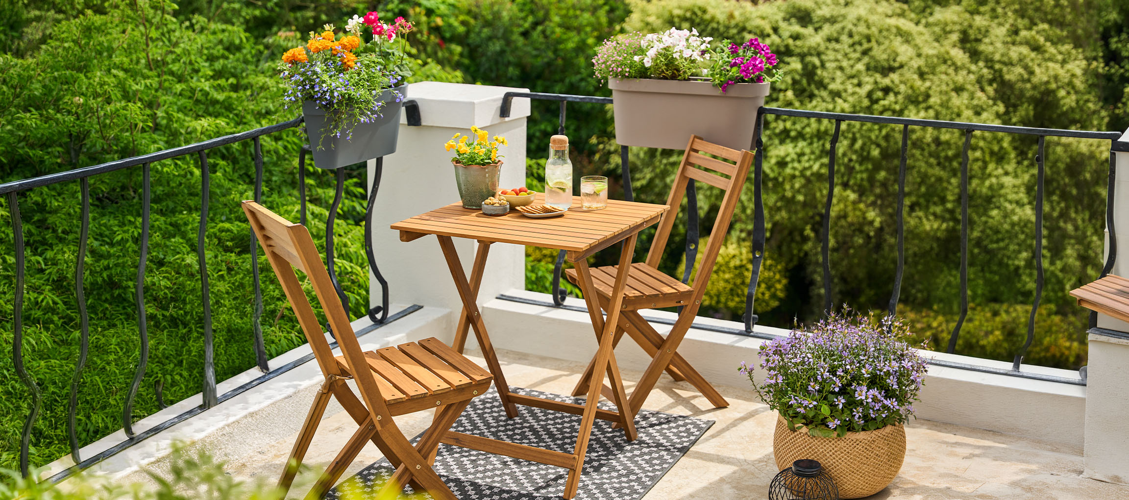 Ensemble de mobilier de balcon avec table et chaises pliantes, décoré de pots de fleurs.