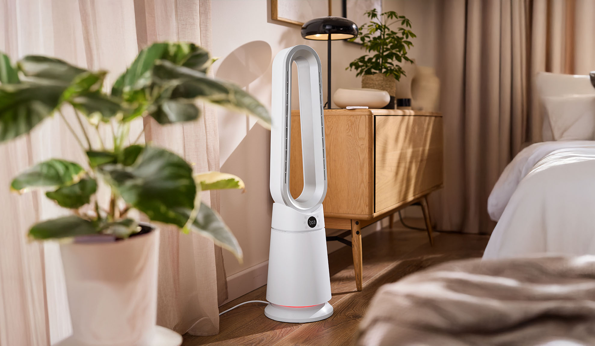 Ventilateur tour blanc dans une chambre moderne avec plantes et meubles en bois.