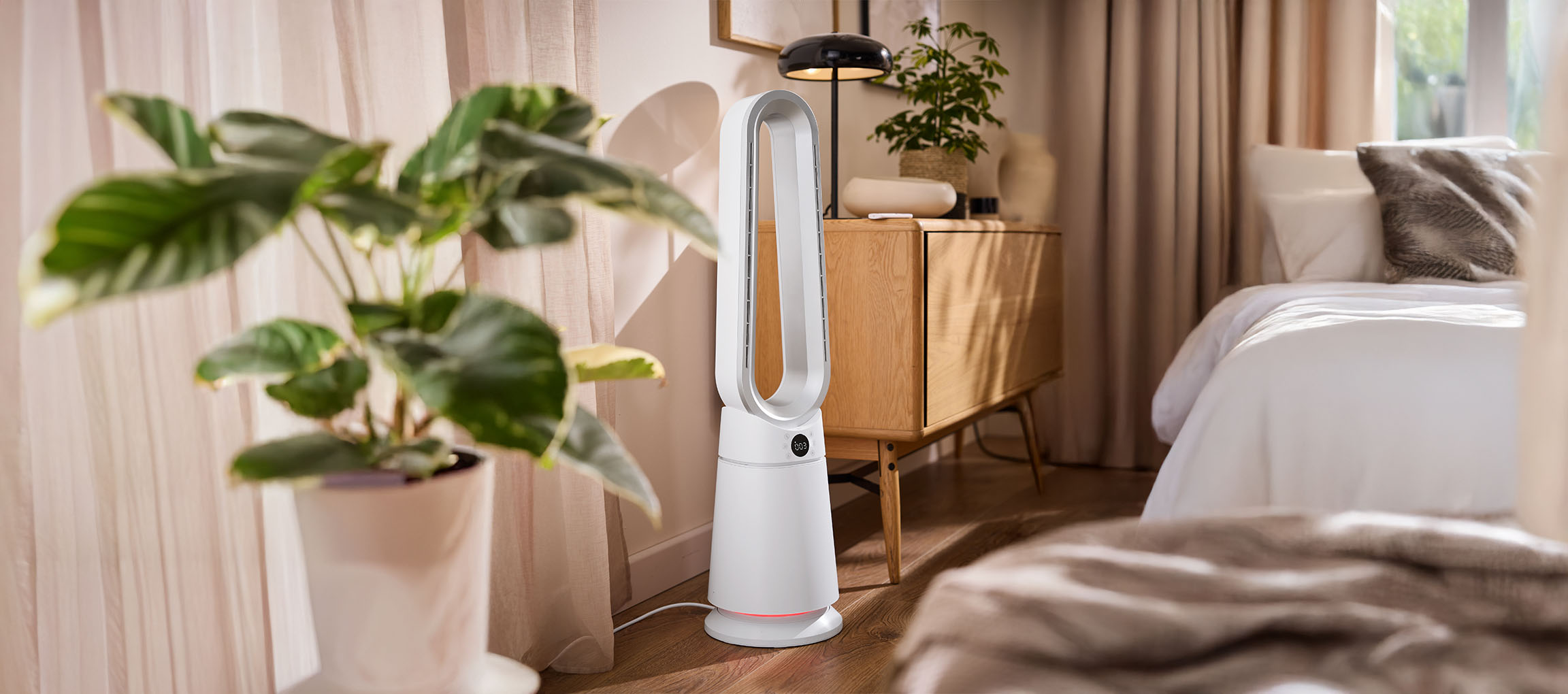 Ventilateur tour blanc dans une chambre avec plantes et meubles en bois.