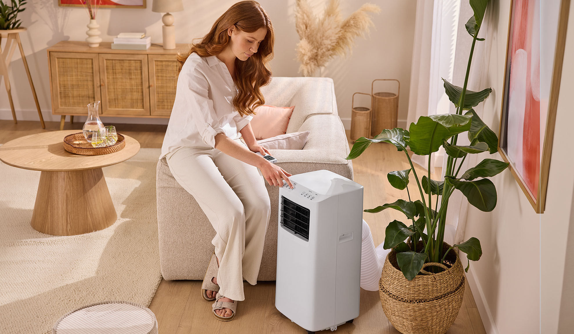 Femme réglant un climatiseur portable dans un salon confortable.