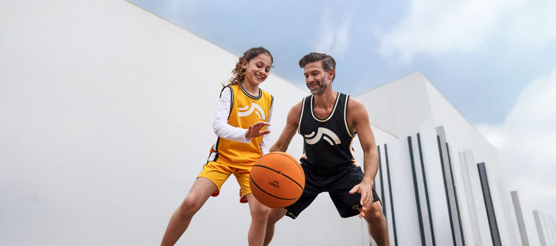 Père et fille jouant au basket avec des tenues de basket et un ballon