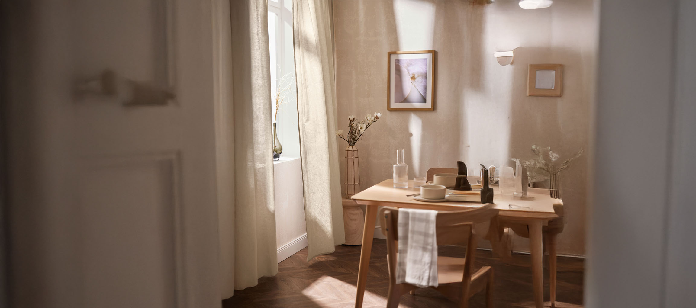 Salle à manger lumineuse avec table en bois, chaises et décorations minimalistes.