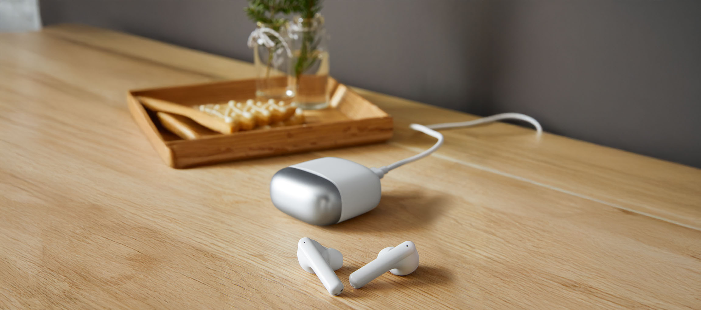 Écouteurs blancs et chargeur portable sur une table en bois.