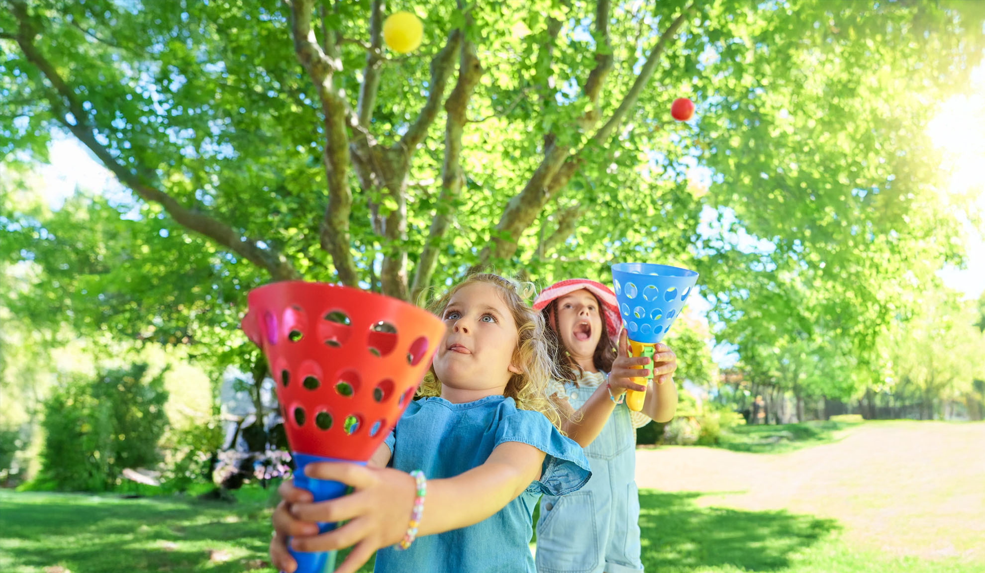 Deux filles jouent à un jeu de capture en plein air avec des attrape-balles en plastique colorés et des balles.