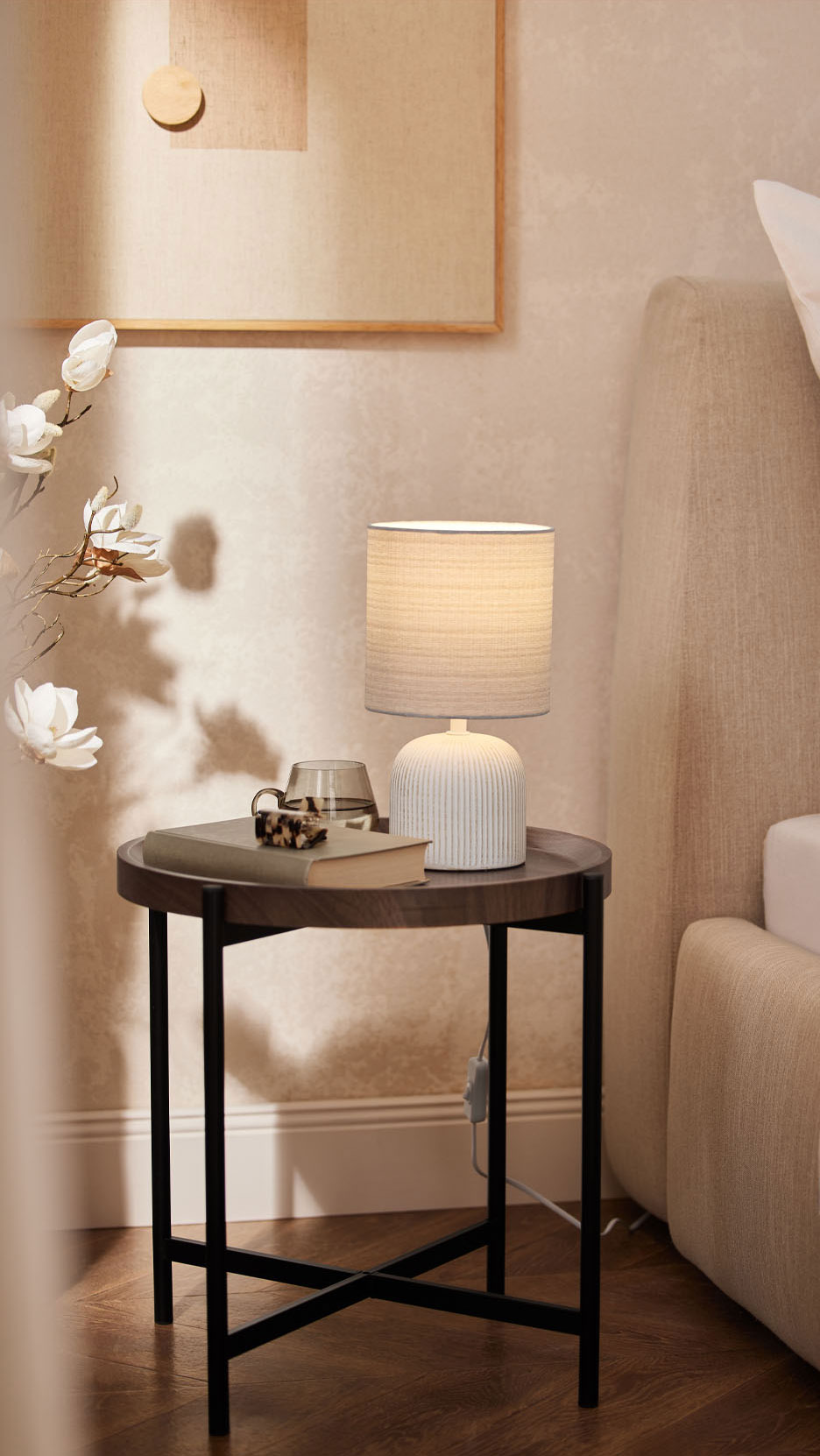 Une lampe de table avec un abat-jour en tissu sur une table de chevet près du lit.