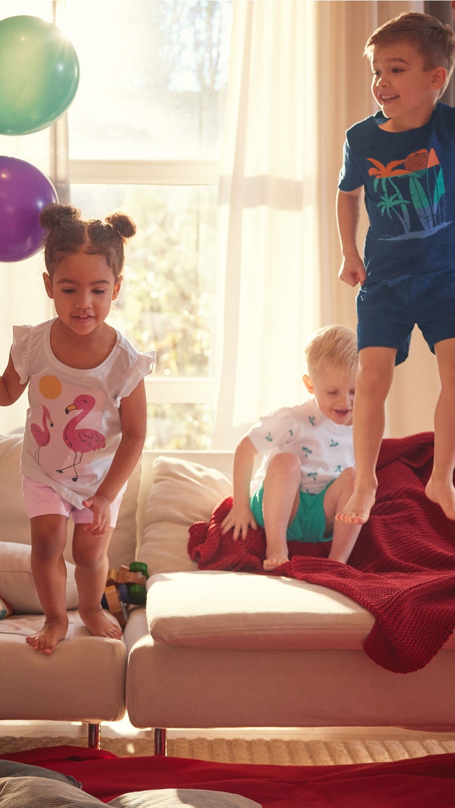 Trois enfants jouent à la maison avec des ballons.
