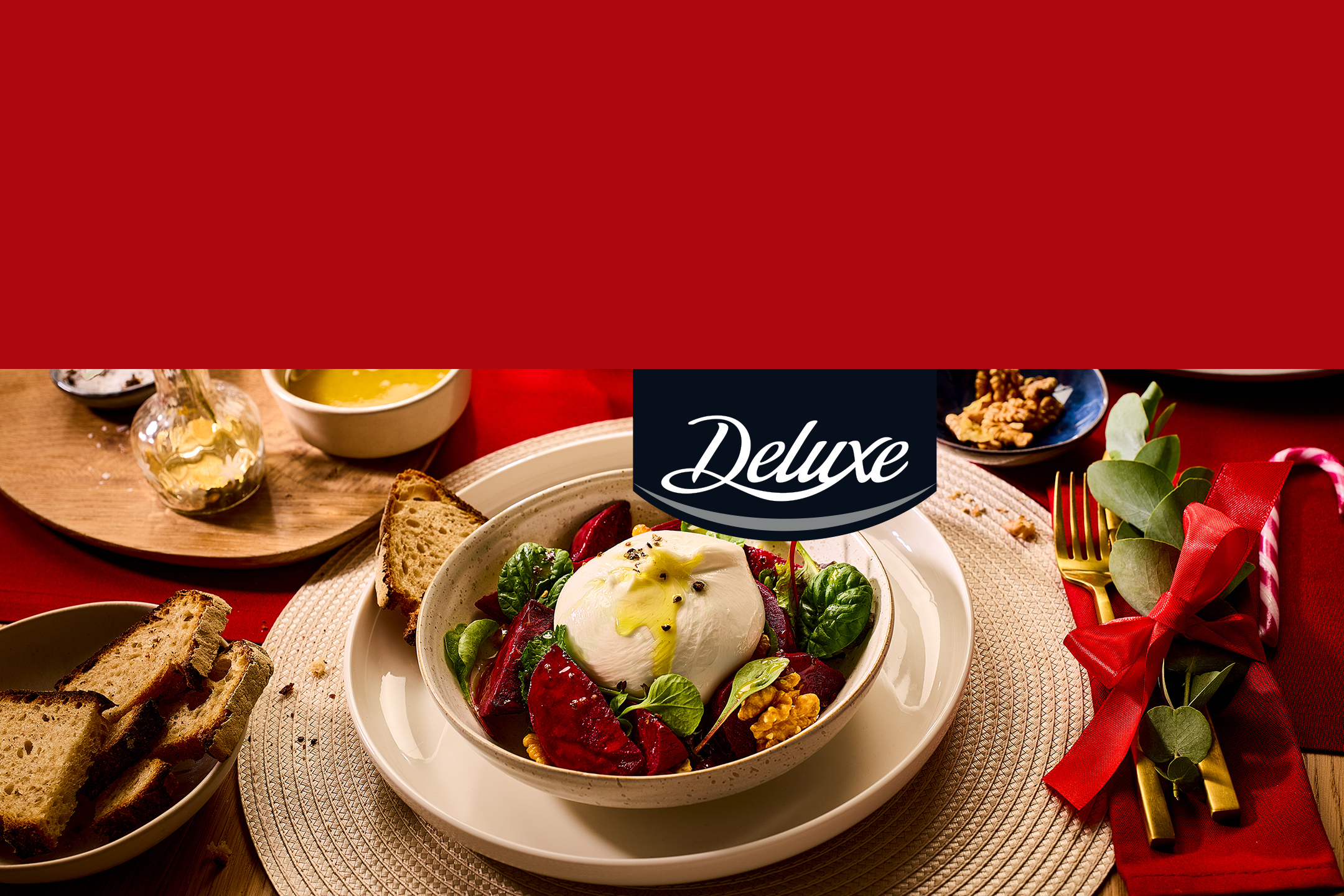 Salade de burrata, betteraves, noix et épinards, avec du pain, sur une table de Noël, logo Deluxe.
