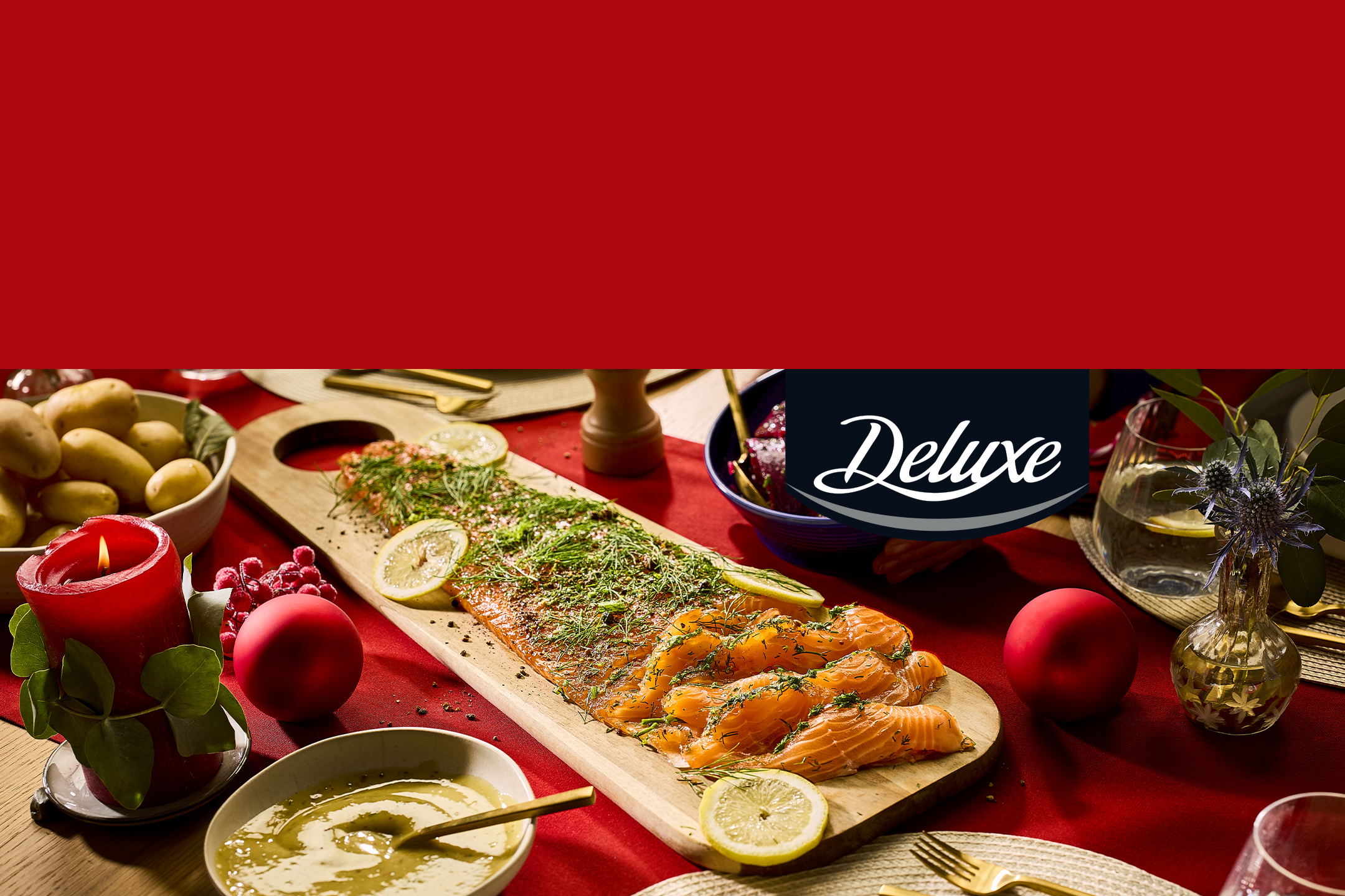 Saumon fumé Deluxe sur une table de fête rouge avec des bougies et des pommes de terre.
