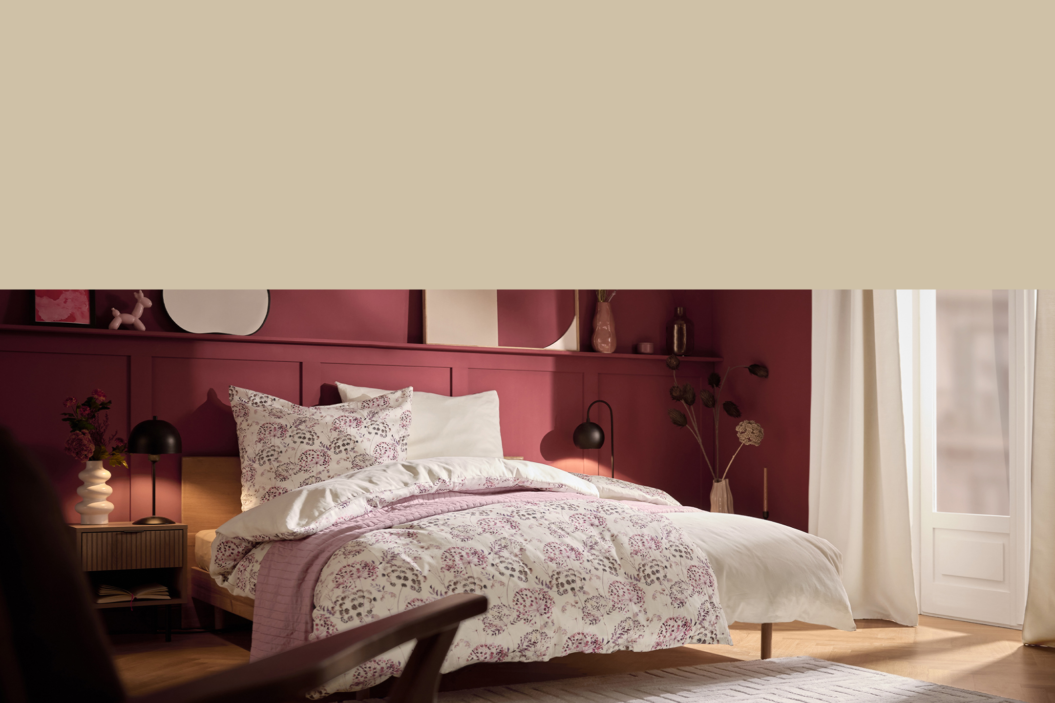 Chambre à coucher avec un lit double, une parure de lit à motifs floraux et des murs bordeaux.