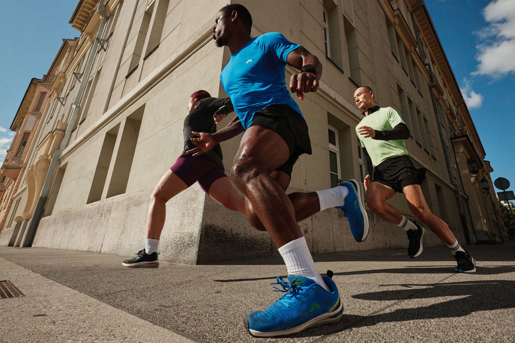 Trois hommes courent en ville, vêtus de t-shirts de sport et de shorts.
