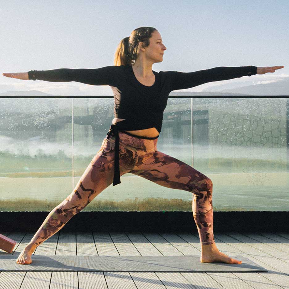 Femme en leggings et haut de yoga sur une terrasse
