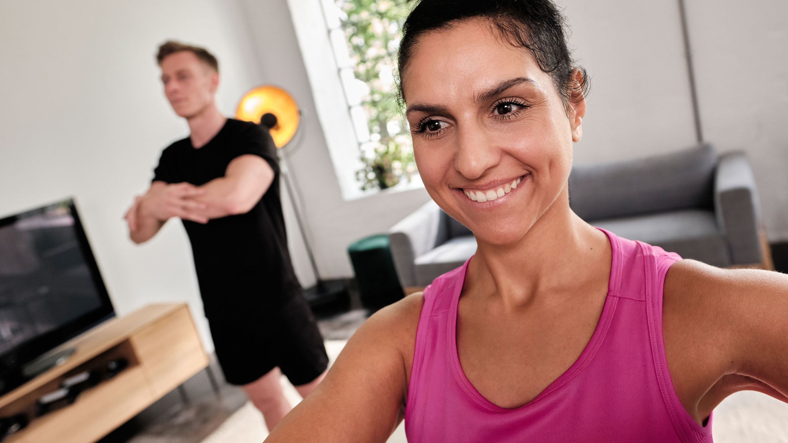 Femme souriante faisant de l'exercice à la maison avec son partenaire.