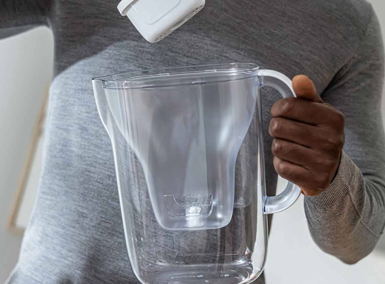 Une personne place un filtre dans un pichet filtrant à eau.