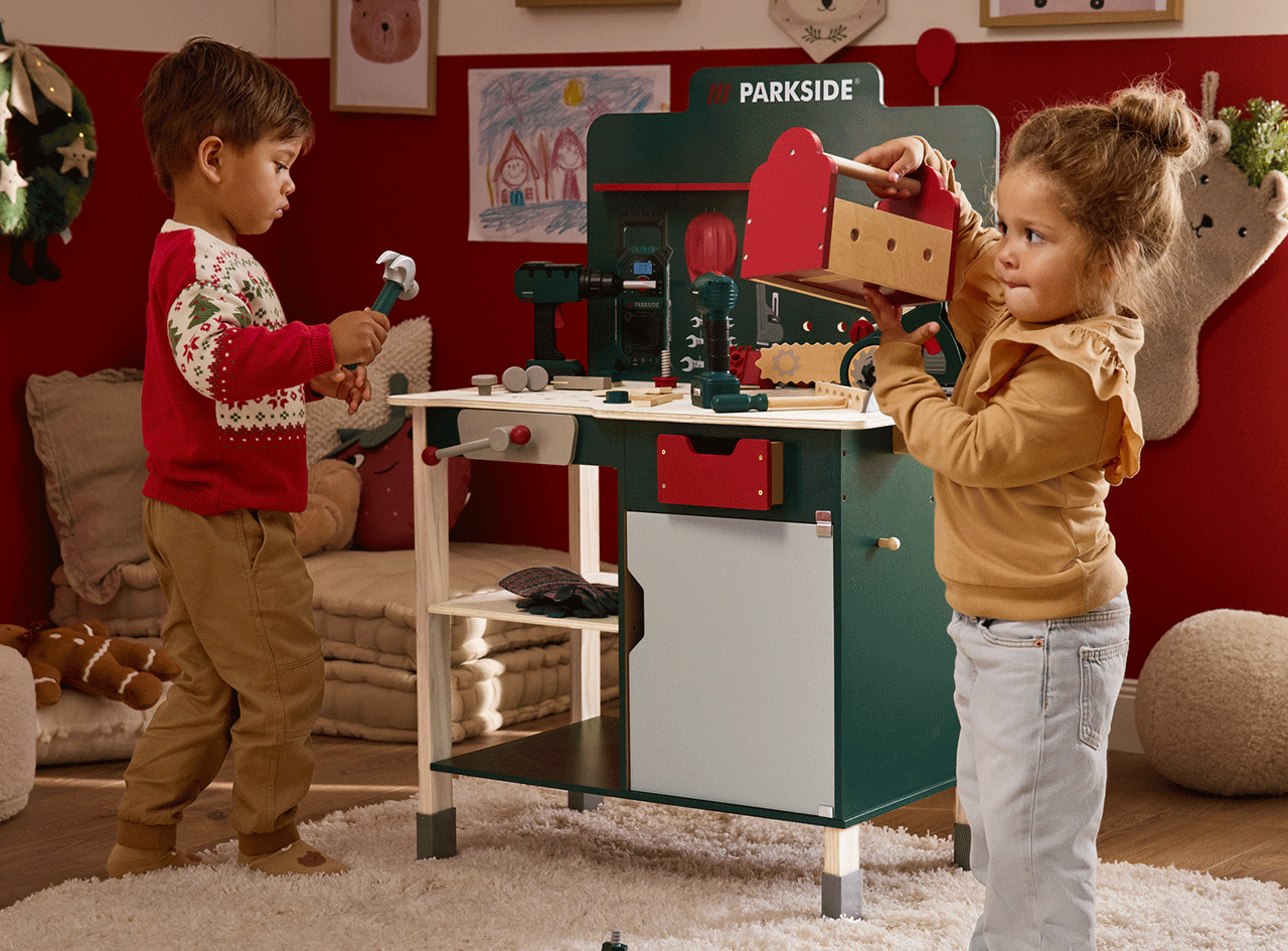 Deux enfants jouent avec un établi et des outils Parkside dans un décor de Noël.