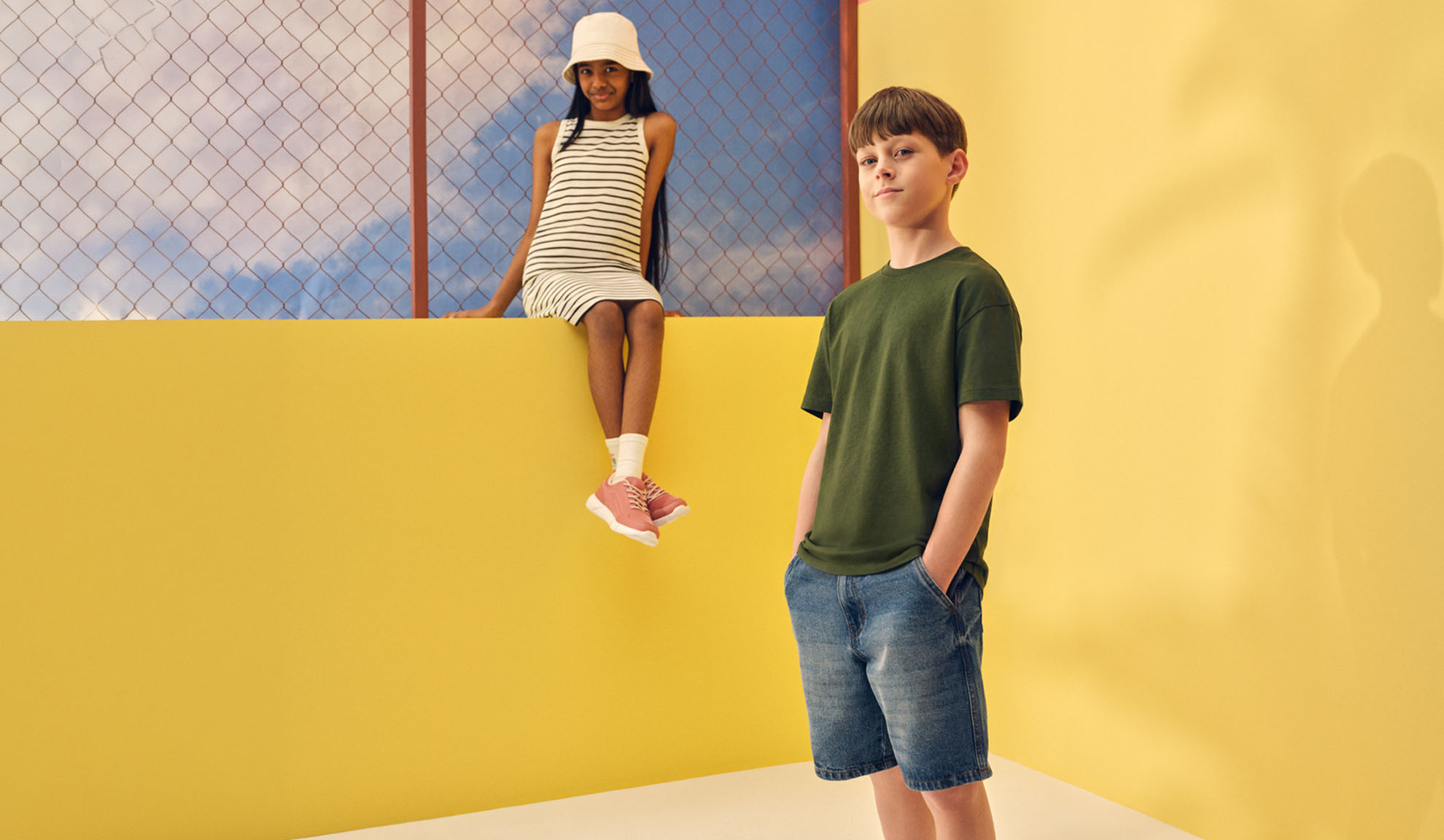 Fille en robe rayée et garçon en t-shirt et short en jean.