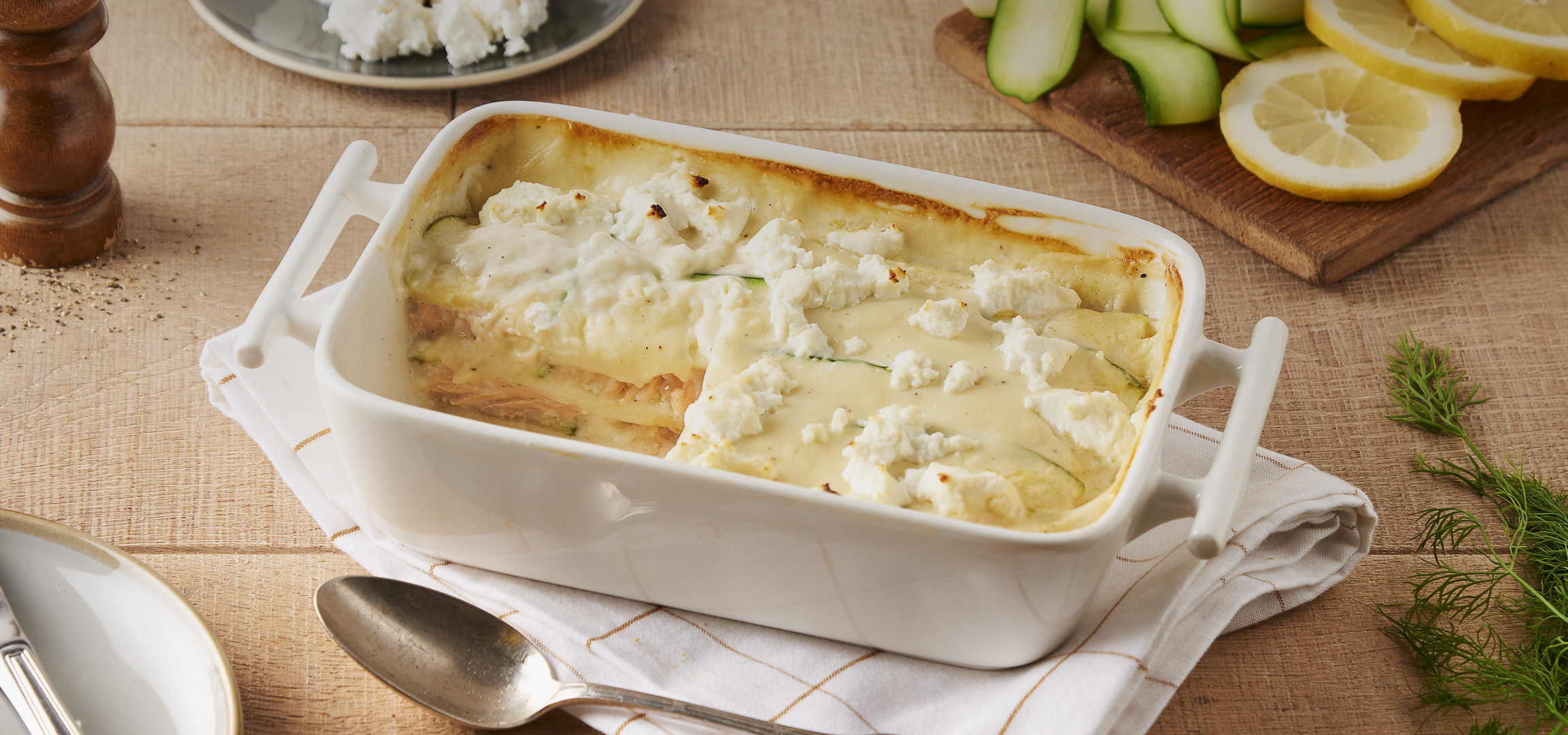 Lasagnes au saumon et aux courgettes avec du fromage frais, sur une table en bois.