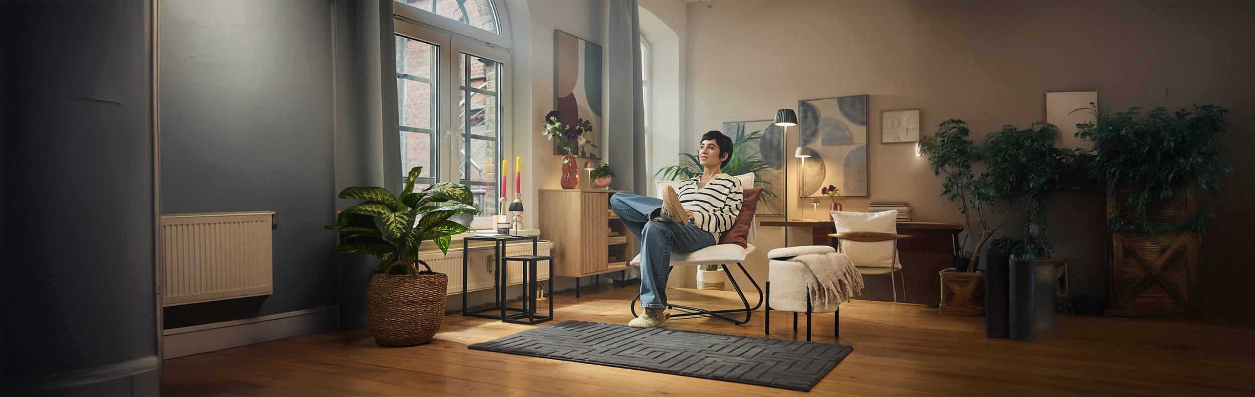 Une femme se détend dans un salon moderne avec des meubles en bois et des plantes.
