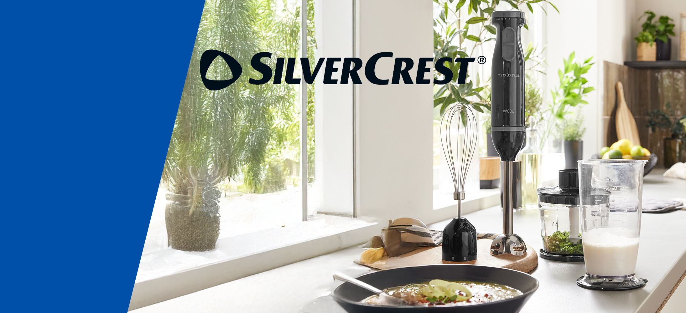 Un mixeur plongeant SilverCrest avec ses accessoires est présenté sur un comptoir de cuisine.