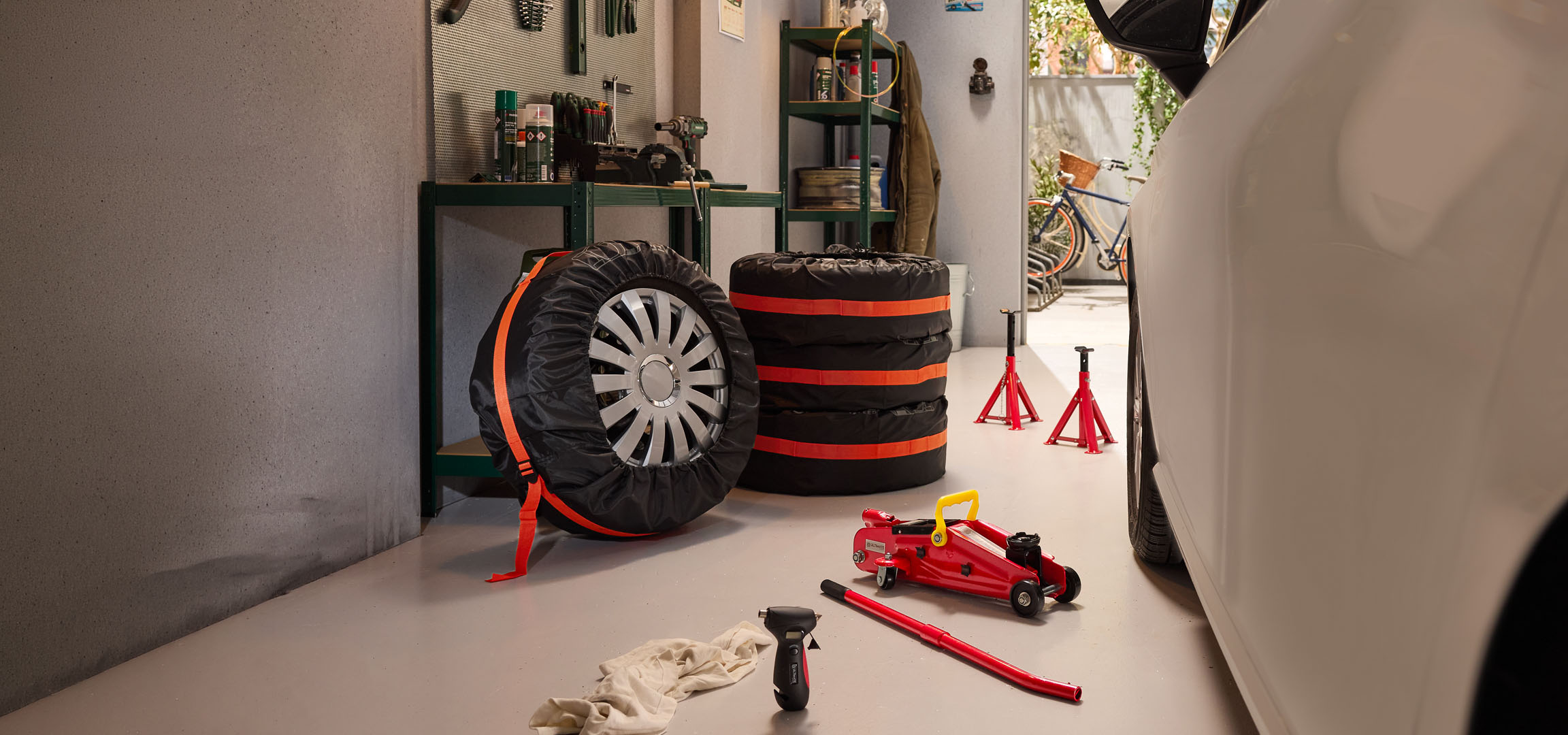 Pneus hiver stockés dans un garage avec un cric hydraulique et des chandelles.