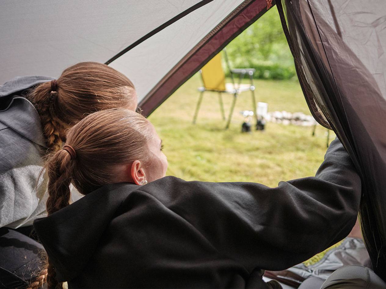 Deux filles regardent par l'ouverture d'une tente.
