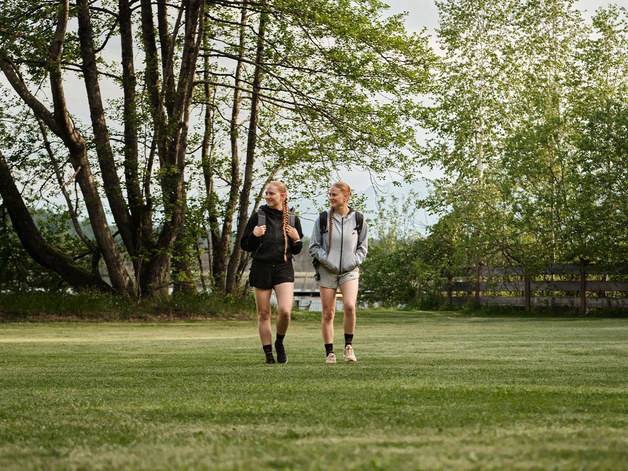 Deux filles avec des sacs à dos marchent sur une pelouse.